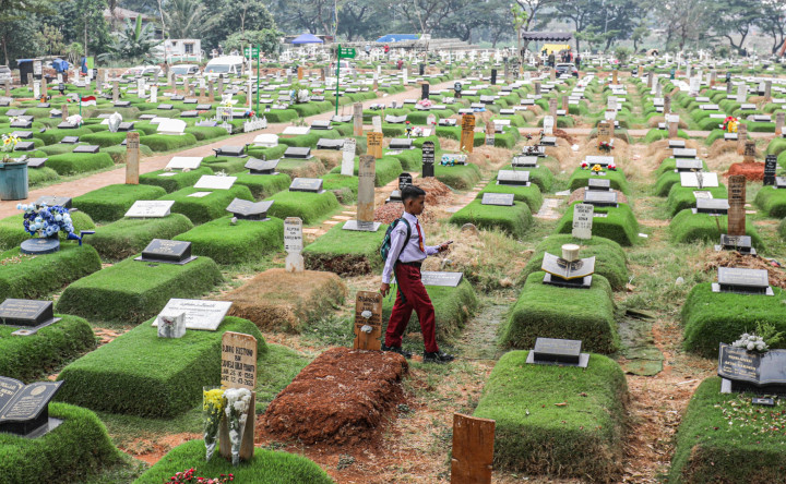 Pelajar melintas di area pemakaman umum (TPU) Karet Bivak, Jakarta, Selasa, 27 Oktober 2026. Dari 80 TPU di Ibu Kota, sebanyak 69 TPU telah penuh dan hanya melayani pemakaman dengan sistem tumpang. 