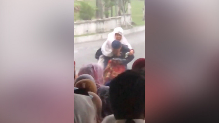 Hujan Mengguyur saat Salat Id, Seorang Anak Gendong Ibunya ke Tempat Teduh