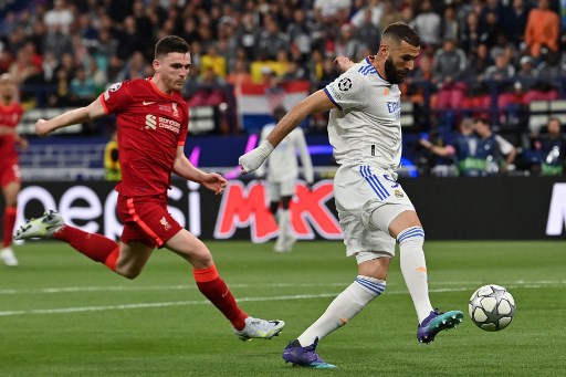 Striker Real Madrid Karim Benzema sedang menghindari kejaran bek Liverpool Andrew Robertson pada final Liga Champions 2021--2022.(Paul ELLIS / AFP)